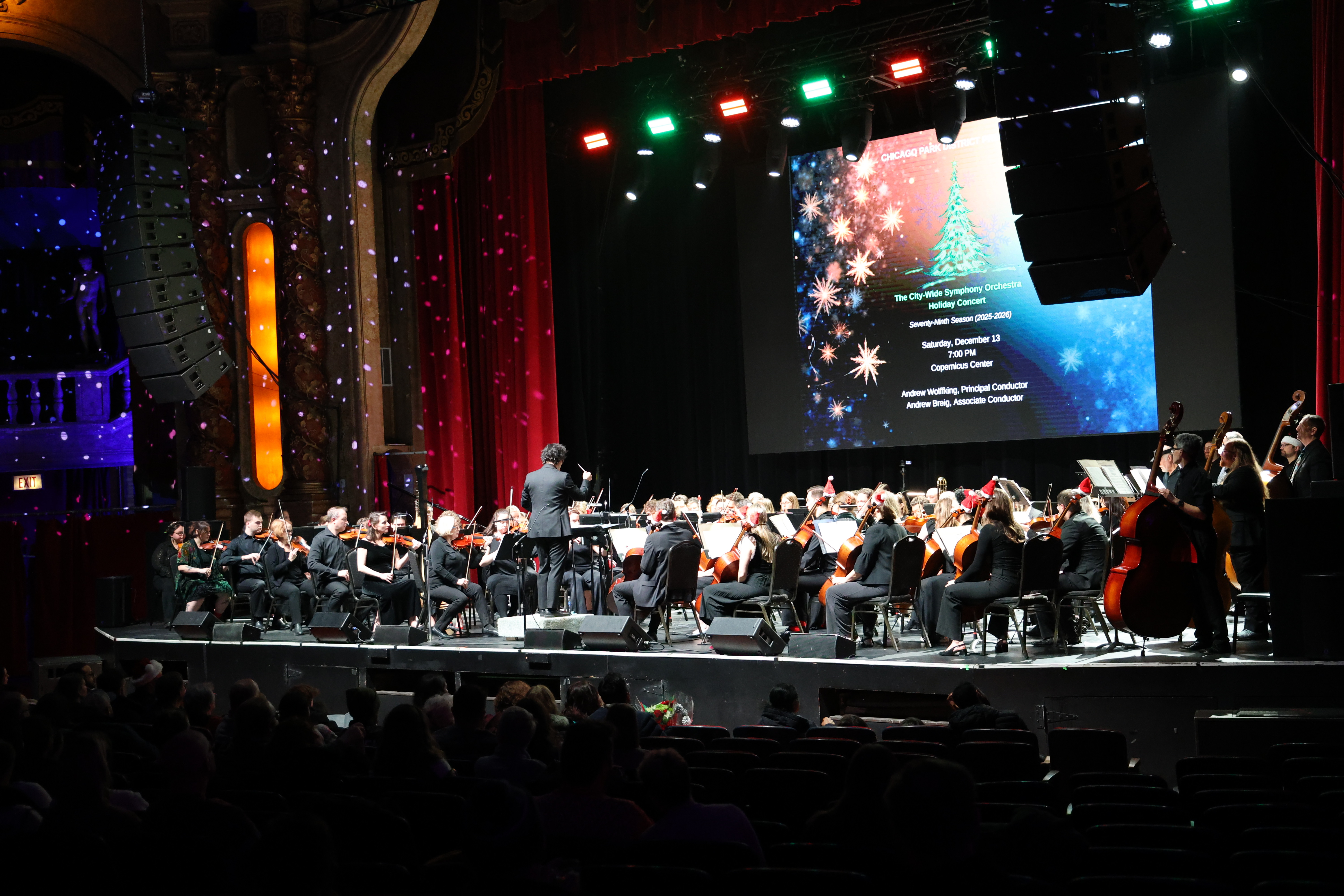 Orchestra performing on stage with conductor.